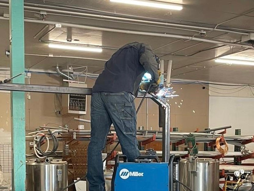 Welder building a custom steel tube frame on a flatbed truck in the Crystal Creek Independence shop